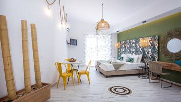 Une chambre à coucher moderne avec un lit, une table de chevet et une chaise. On y trouve une fenêtre avec des rideaux, un téléviseur fixé au mur et un miroir décoratif.