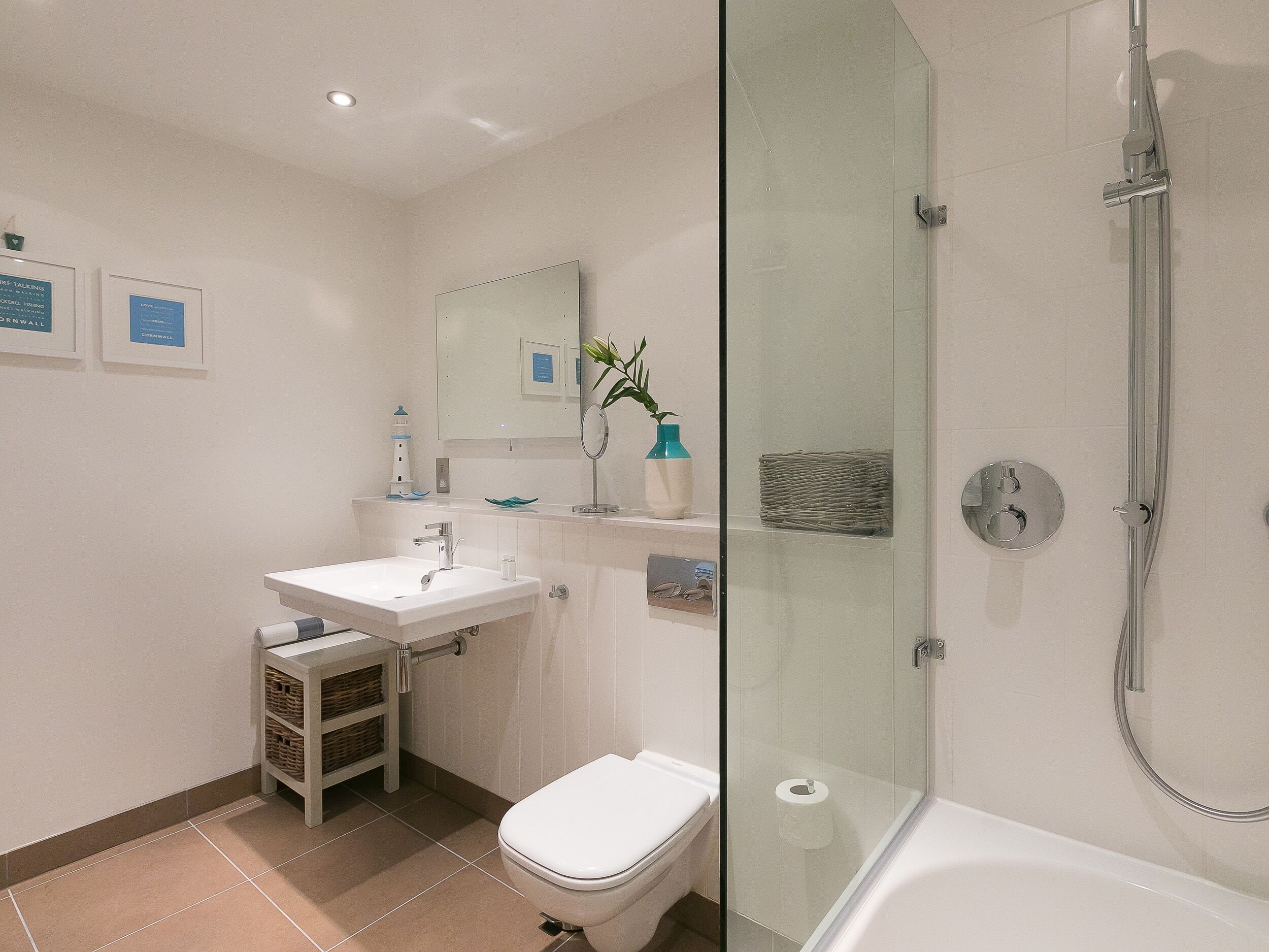 A modern bathroom with a glass-enclosed shower, a white sink, and a toilet.