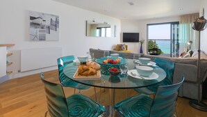 Un salon moderne avec une table à manger en verre, des chaises de couleur turquoise et un canapé.