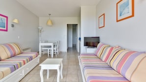 Een moderne woonkamer met gestreepte banken, een eettafel en een televisie.