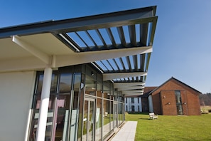 A modern building with large glass windows and a covered patio area.