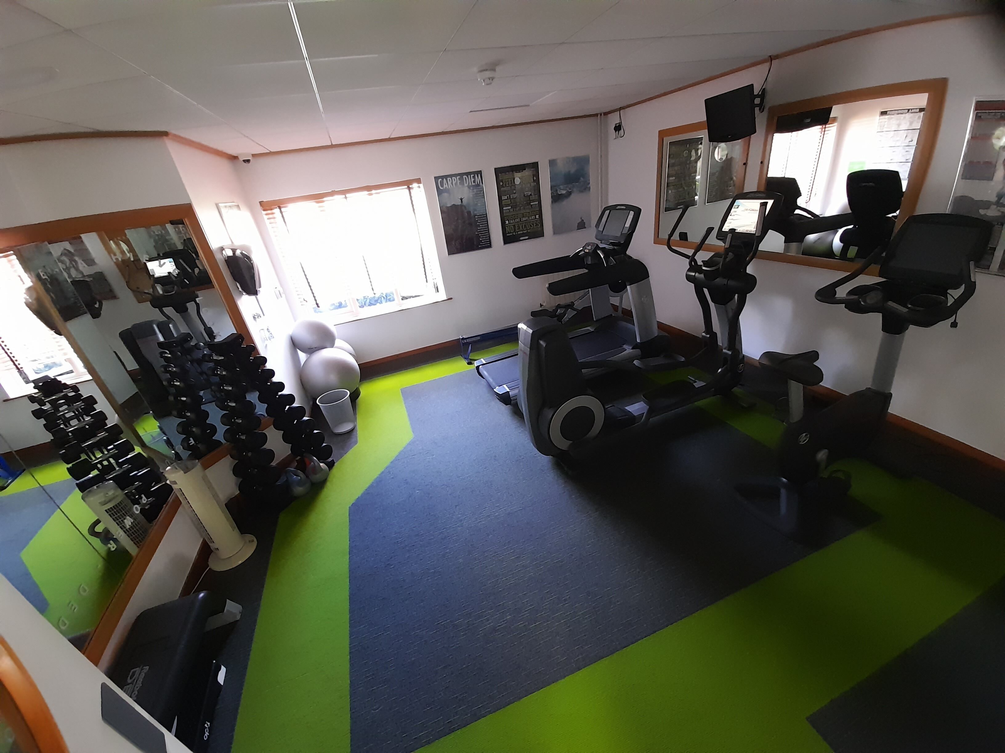 A gym with exercise equipment, a treadmill, and dumbbells.