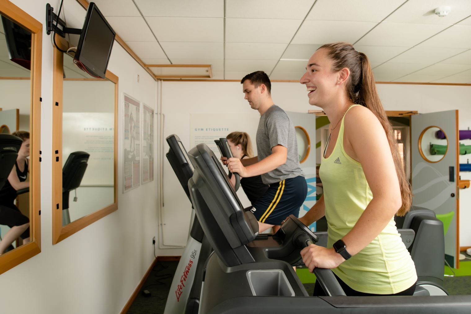 Ett gym med löpband, speglar och träningsredskap.