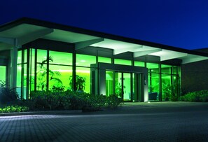 Un edifici modern amb grans finestres de vidre i un interior il·luminat amb llum verda.