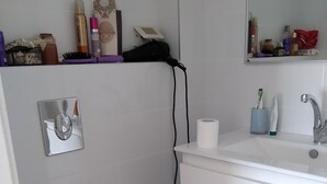 A bathroom with a white toilet, a sink with a mirror, and toiletries on the countertop.