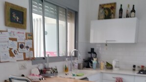 A modern kitchen with a wooden table, two chairs, a sink, and various kitchen items.
