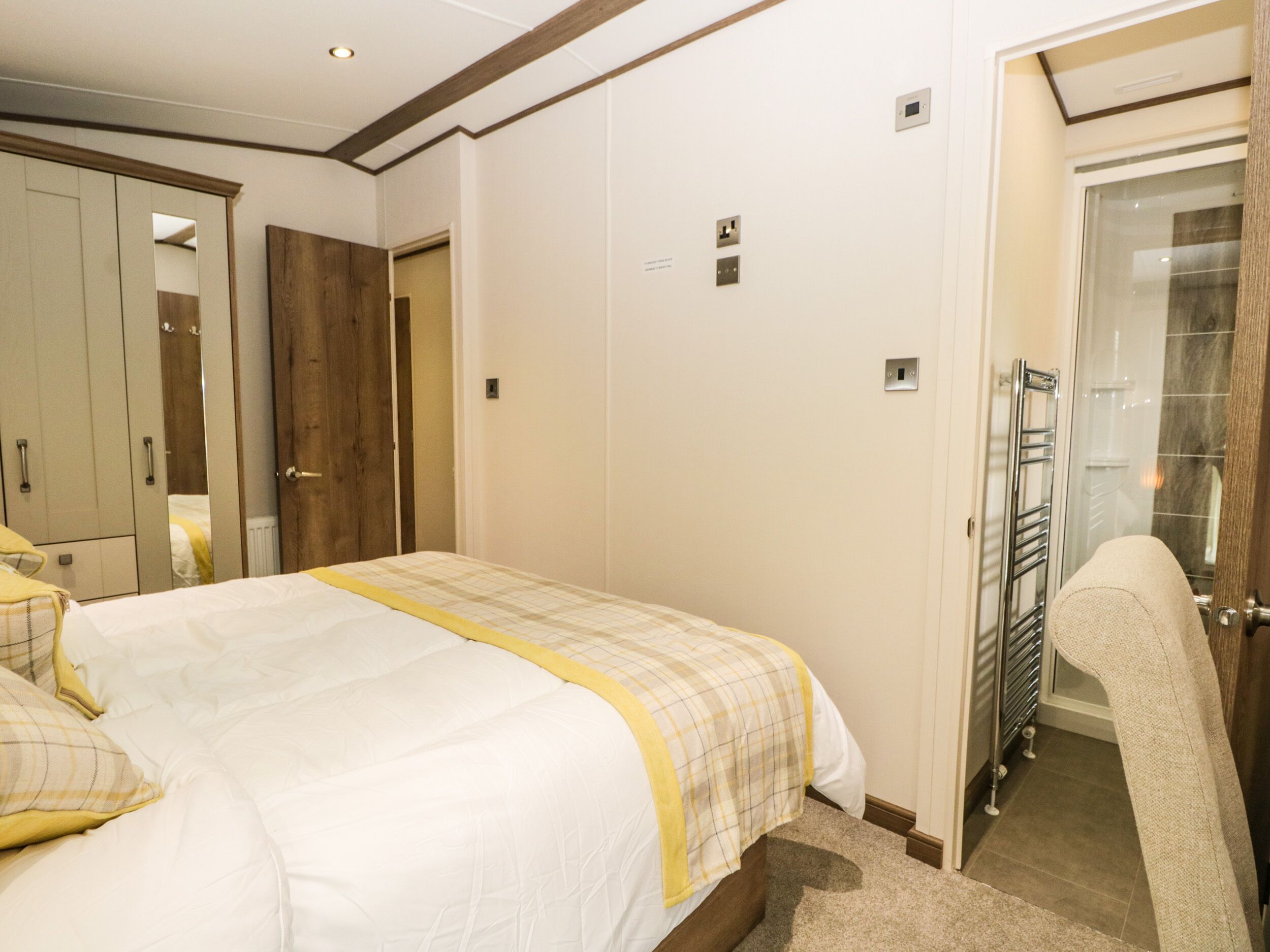 Un dormitorio con cama, armario, una puerta que da a un baño y un perchero.