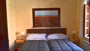 Ein Schlafzimmer mit zwei Betten, Holz-Kopfteilen und einem großen Landschaftsbild darüber.