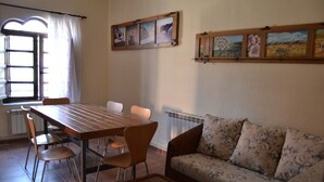 Ein Essbereich mit Holztisch und Stühlen, einer Couch und einem Fenster mit Vorhängen.