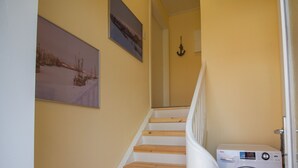 A staircase with wooden steps and white railings, leading to a landing with a white door and a Haier appliance.