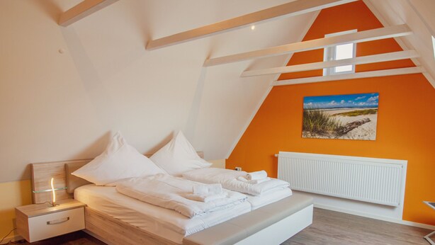 A bedroom with a bed, nightstand, and a painting on the wall.