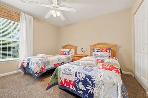 A bedroom with two single beds, a ceiling fan, and a window with blinds. - TB 66A Three Bedroom/Two Bath unit in True Blue (Pawleys island)
