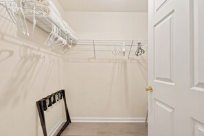 A walk-in closet with a metal drying rack, a black shoe rack, and a white door.