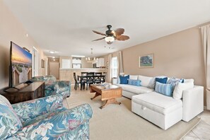 A living room with a white sofa, floral armchairs, a wooden coffee table, and a ceiling fan. - TB 66A Three Bedroom/Two Bath unit in True Blue (Pawleys island)