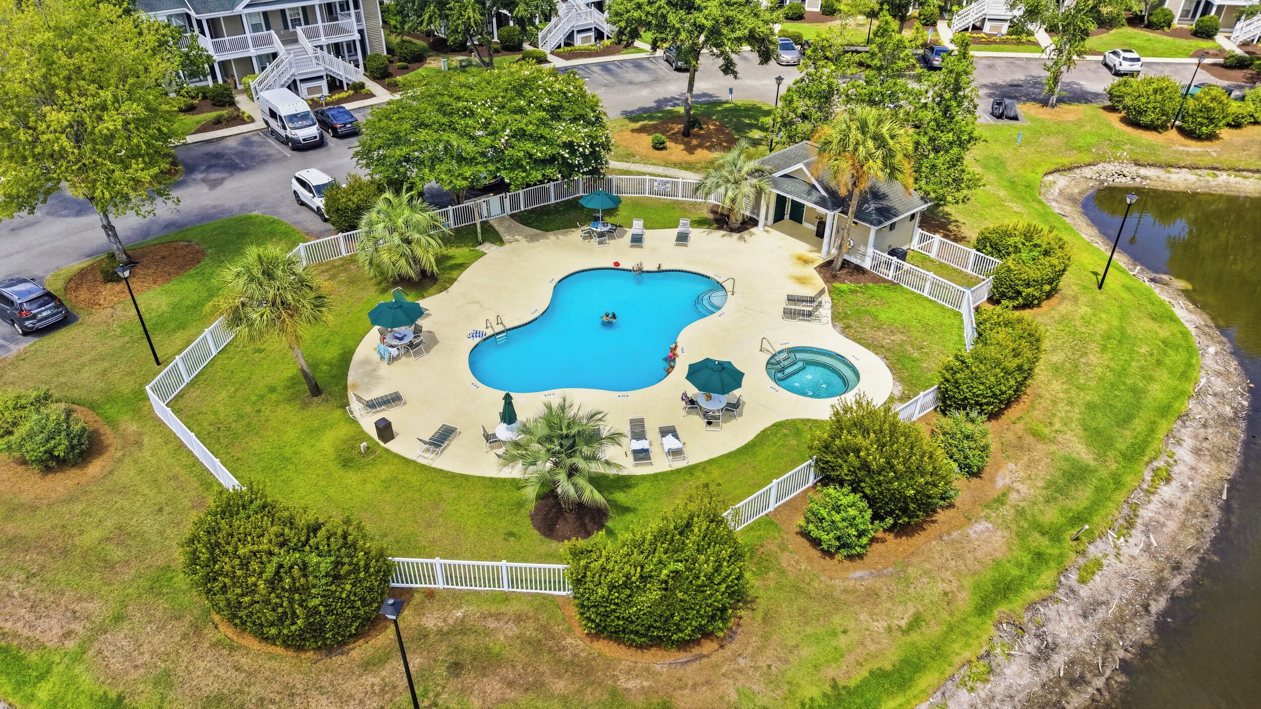 A residential area with a swimming pool, lounge chairs, and a small deck.