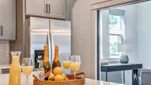 A kitchen with a refrigerator, a dining table with a basket of lemons, and two glasses of orange juice. - Beautiful Luxury Renovation, 5 minutes to Downtown (Nashville)