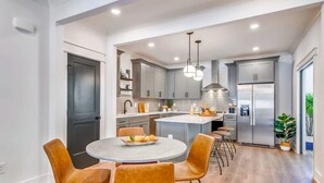 Una cocina moderna con gabinetes grises, una isla central y un refrigerador de acero inoxidable.