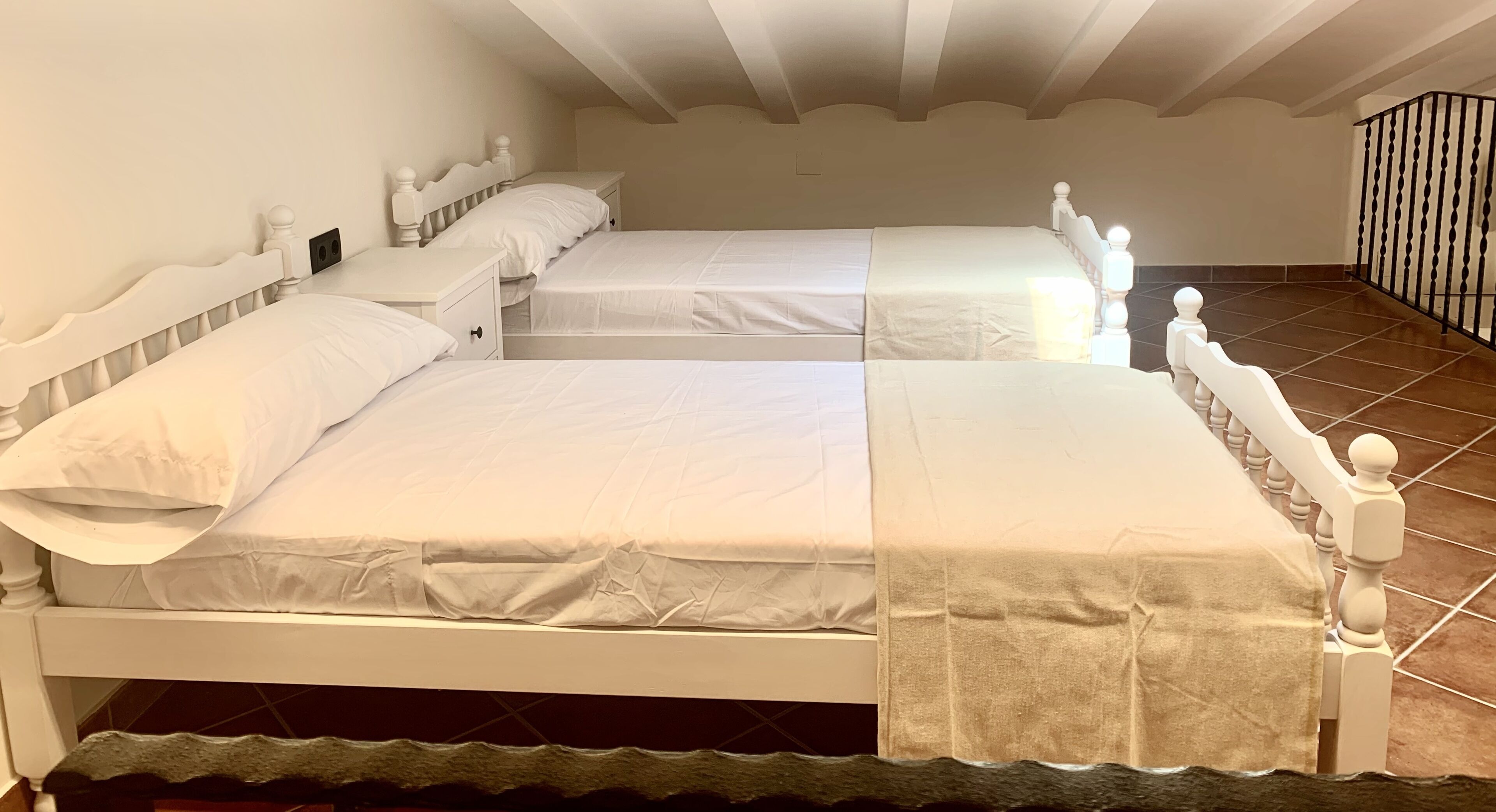 Un dormitorio con dos camas, ropa de cama blanca y suelo de baldosas.