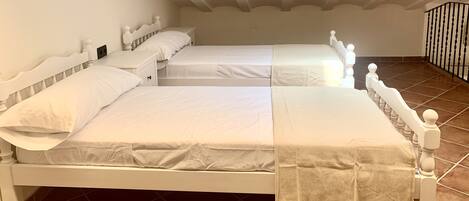 Un dormitorio con dos camas, ropa de cama blanca y suelo de baldosas.