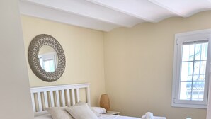 A neatly arranged bedroom with a bed, pillows, a bedside table, a lamp, and a window. - Bio Resort Mediterraneo (Sant Martí Sarroca)