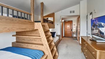Une chambre d’hôtel moderne avec un escalier en bois, un lit, un bureau et une télévision.
