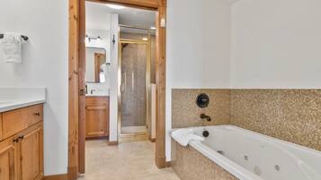 A modern bathroom with a walk-in shower, wooden cabinets, and a large bathtub.