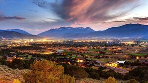 Une vue panoramique d’une ville, avec une chaîne de montagnes en arrière-plan, où l’on aperçoit un mélange de bâtiments résidentiels et commerciaux.