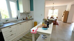 Una cocina moderna con armarios blancos, un tapete a rayas y una zona de comedor con una mesa preparada para dos.