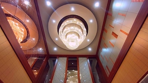 Un interior moderno con una lámpara circular central, baldosas de suelo estampadas y un techo reflectante.