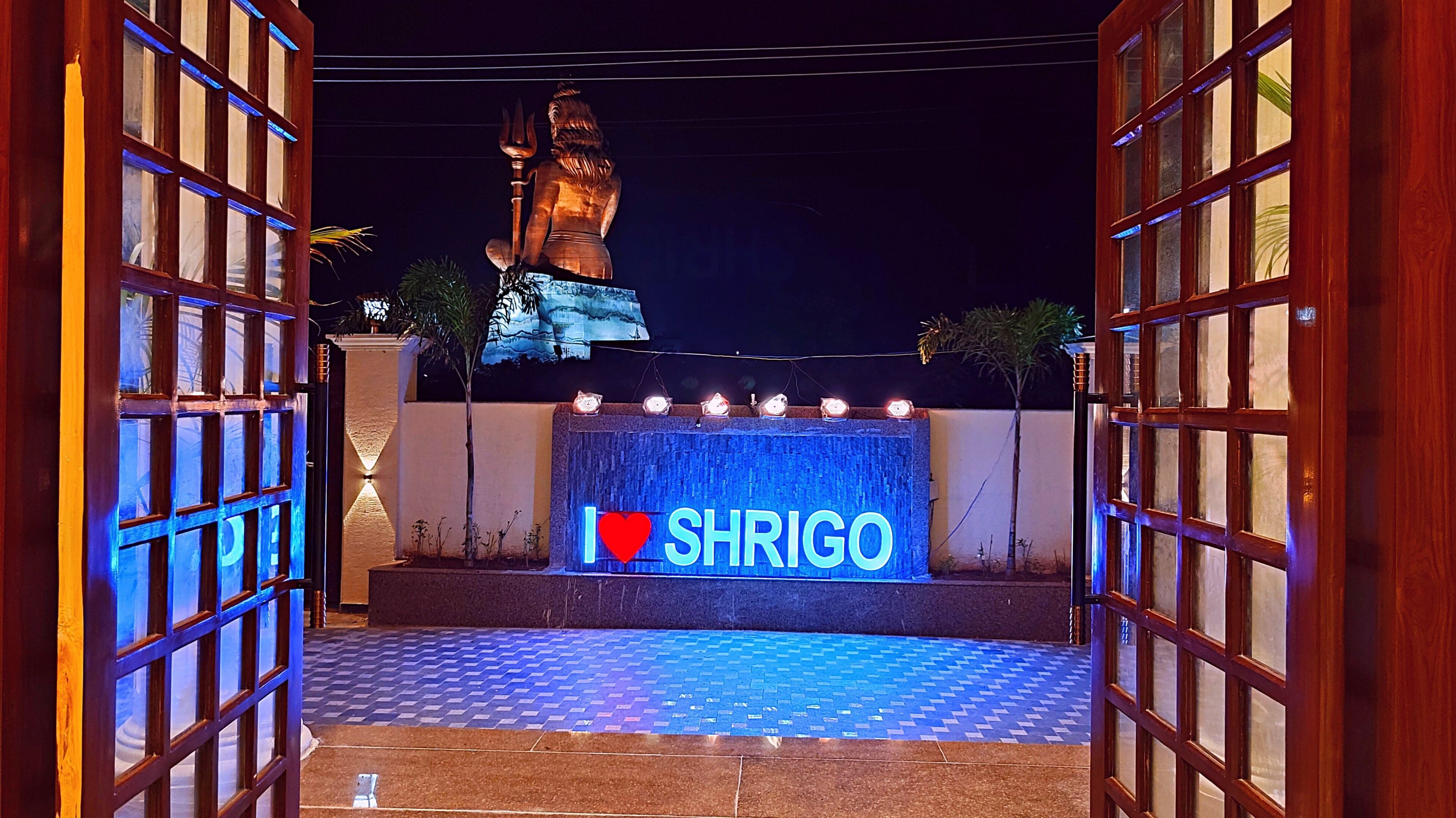 A gated entrance with a sign reading "I ♥ SHRIGO" and a statue in the background.