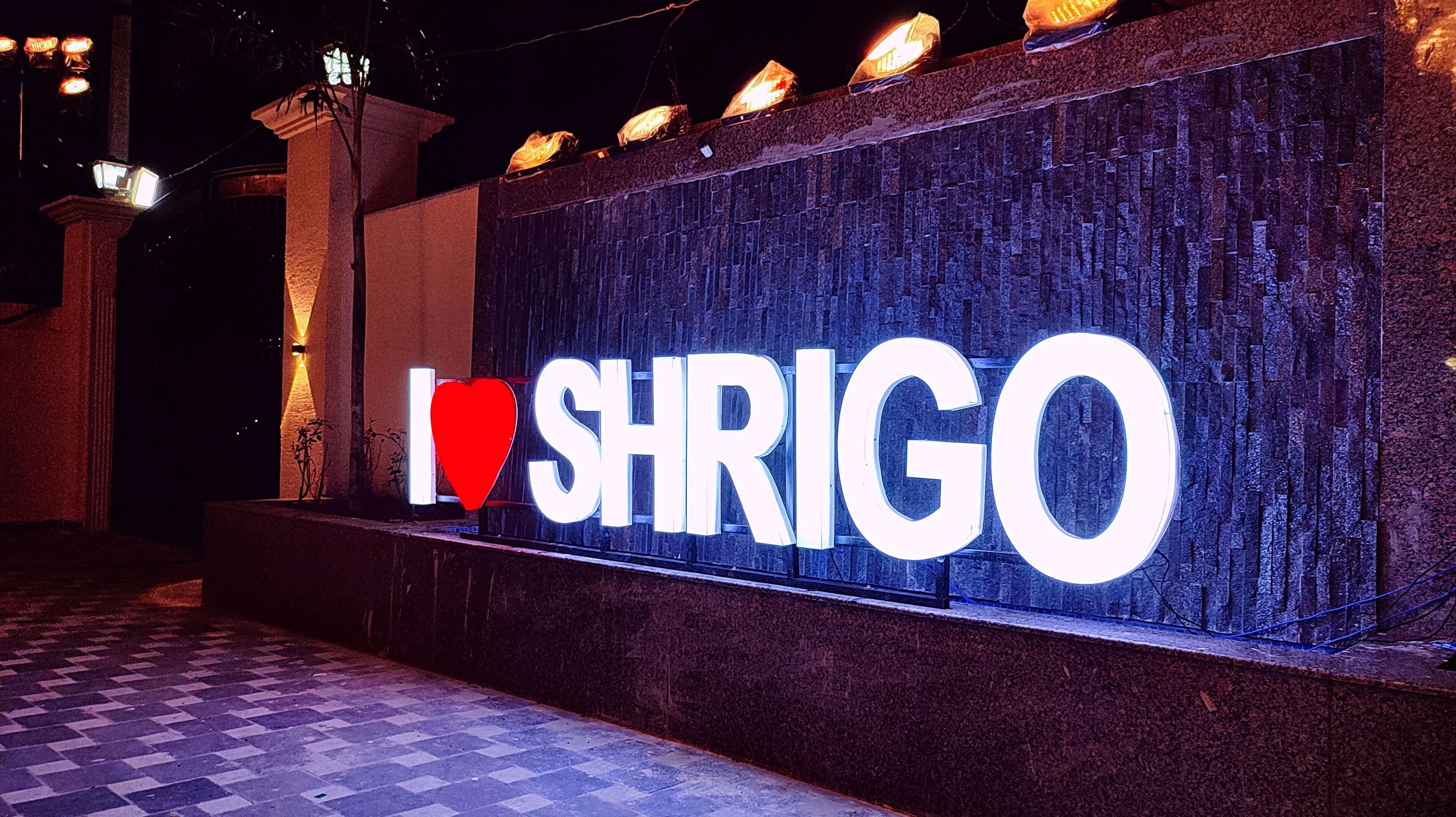 Ein Schild mit dem Schriftzug „Ich liebe SHRIGO“ an einer strukturierten Wand.