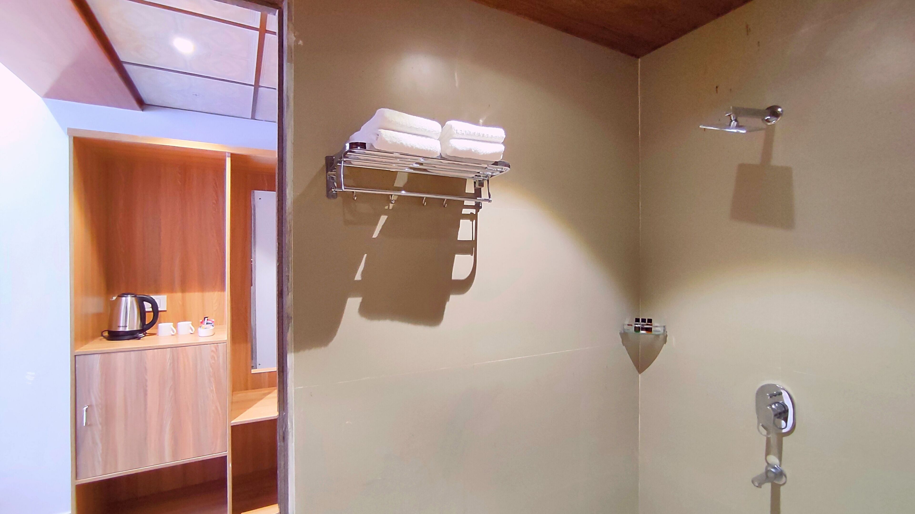 Un bagno con doccia, un portasciuga, un lavandino e un bollitore, oltre a un armadietto in legno.
