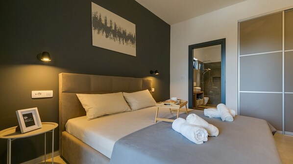A modern hotel room with a large bed, a bedside table, a framed picture, and a bathroom visible through an open door. - Modern Villa Amoroso in western Istria (Nova Vas)