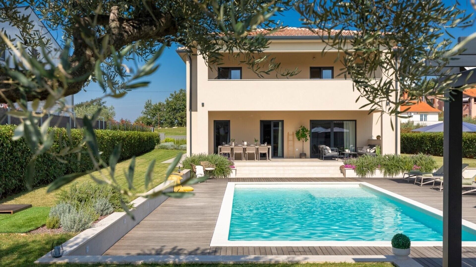 A two-story house with a swimming pool, outdoor seating, and a garden.