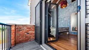 A modern hotel room with a sliding glass door leading to a balcony, a bed with a headboard, and a small seating area. - Modern Villa Baraka with a pool (Kanfanar)