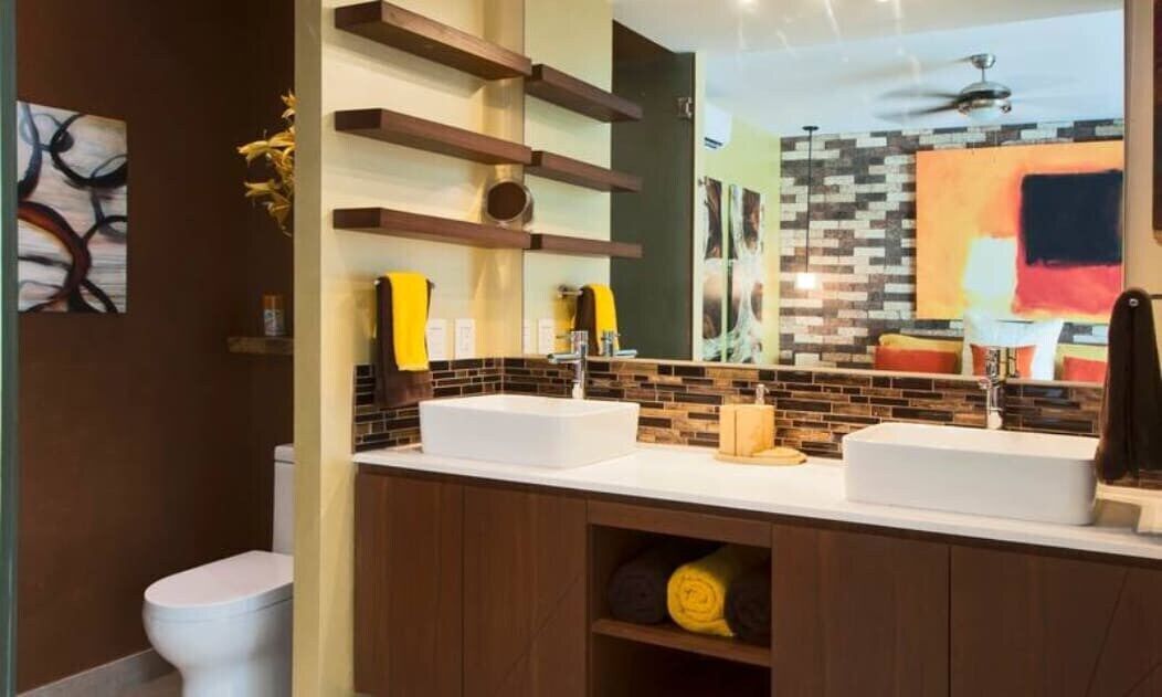 A modern bathroom with two sinks, a large mirror, and a ceiling fan.