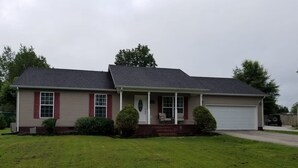 A single-story house with a front porch, a garage, and a well-maintained lawn. - Spacious 3BR 2BA, 11 Min to Cummins Falls Park (Cookeville)