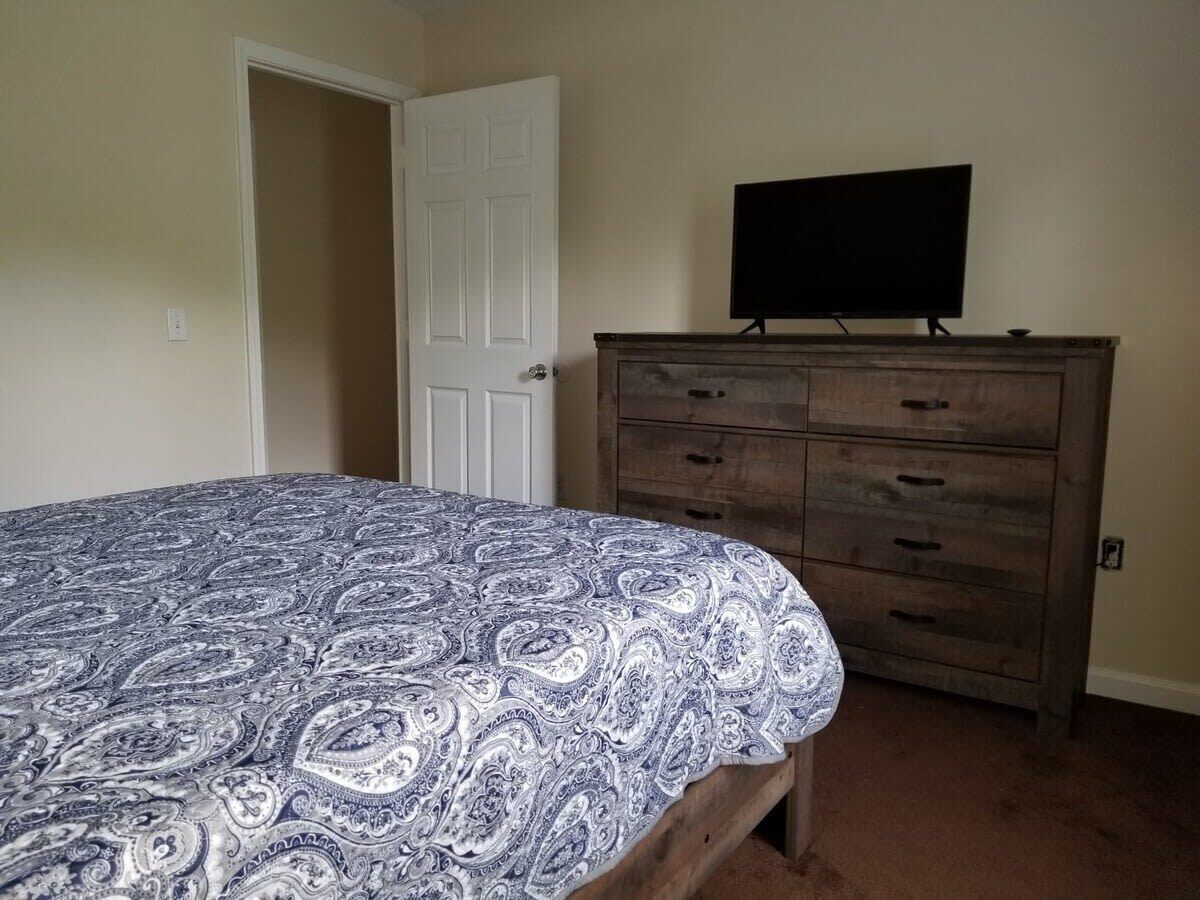 A bedroom with a bed, a dresser, and a television on top.