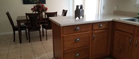 Una cocina con armarios de madera, una encimera y un comedor con sillas y una mesa.