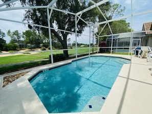 Une piscine dotée d’une terrasse blanche et d’une enceinte en verre.