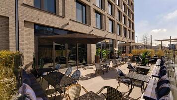 Un patio al aire libre con mesas y sillas, un edificio de ladrillo y vistas de la ciudad.