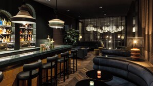 Eine Bar mit Theke, Hockern und einer Sitzecke mit Sofas und runden Tischen.