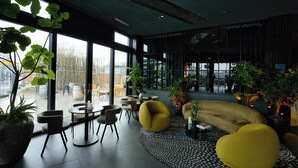 Ein modernes Interieur mit großen Fenstern, Sitzgelegenheiten und Zimmerpflanzen.