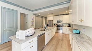 Una cocina moderna con armarios blancos, electrodomésticos de acero inoxidable y encimera de mármol.