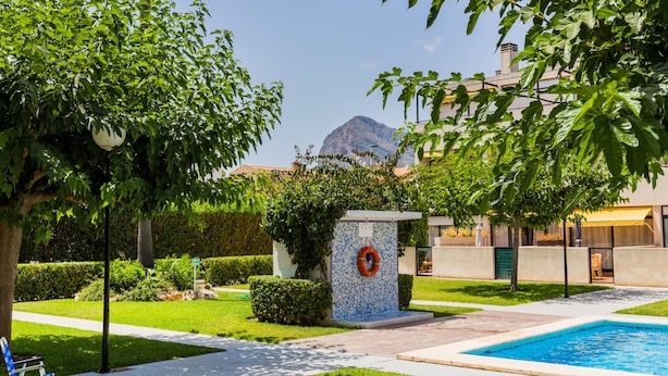 Zona piscina con un salvagente, una panchina e vista su una montagna.