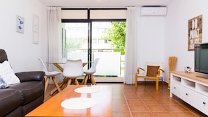 Un soggiorno moderno con un divano, un tavolo in legno, un mobile TV e un balcone con vista sul verde.
