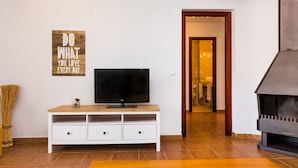 Un soggiorno con televisore su un mobile bianco, un caminetto e un poster motivazionale appeso al muro.