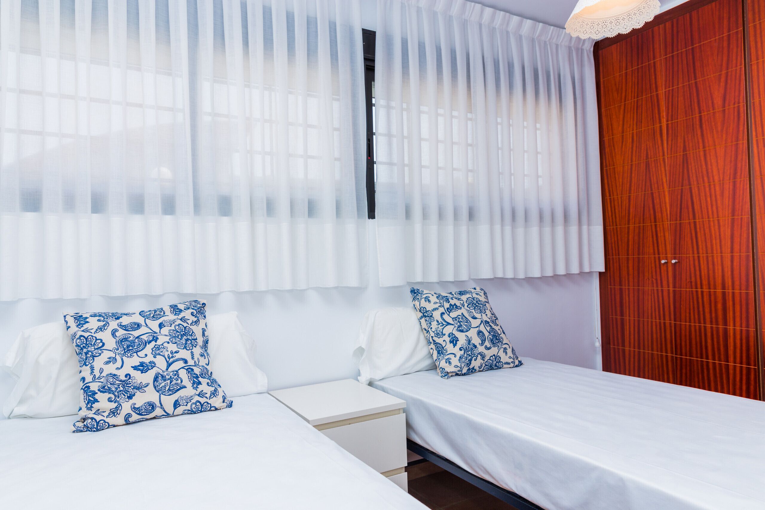 Une chambre avec deux lits, du linge de lit blanc et des coussins à motifs bleus.