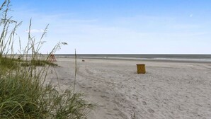 Een zandstrand met weinig begroeiing en een houten constructie.