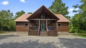 Een houten chalet met een stenen fundering, een veranda en een metalen dak.